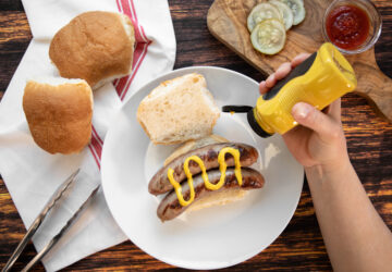 Squeezing mustard onto a brat sandwich